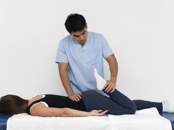 front-view-physiotherapist-doing-leg-exercises-with-woman